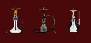 Fotografía de tres cachimbas colocadas sobre un fondo rojo oscuro; cada una presenta un diseño y acabado únicos en cristal."